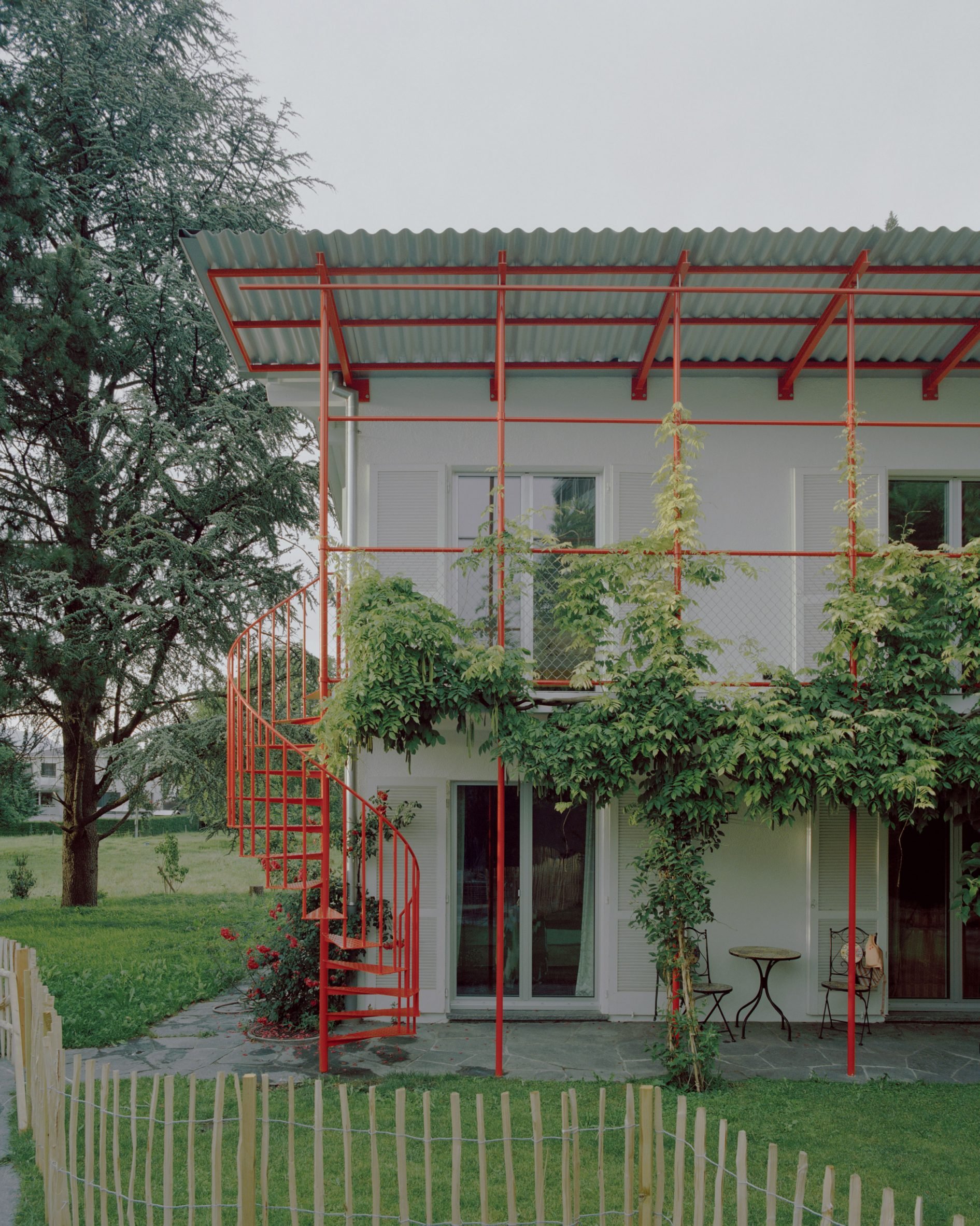 Two residential units connected by red steel staircase and balcony