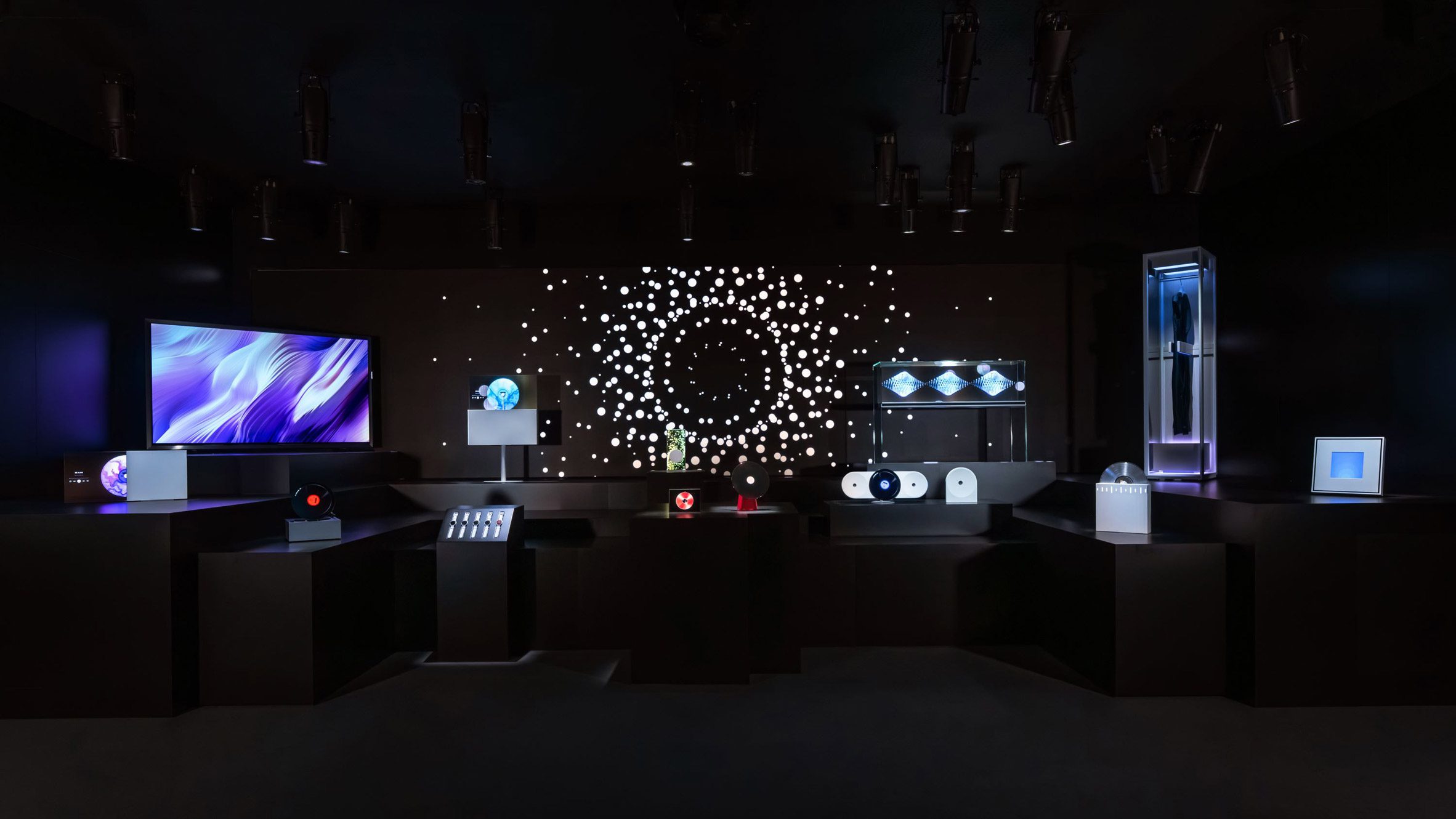 Dark room with illuminated screens, devices and a circular light installation 