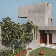 Entrance to the concrete Enclosure house by Design Ni Dukan with concrete canopy and grass lawn