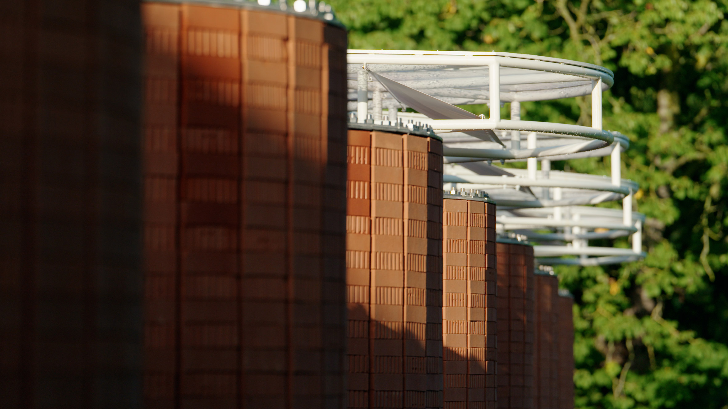Close-up view of the pavilion showing curved brick walls topped by a white steel canopy structure