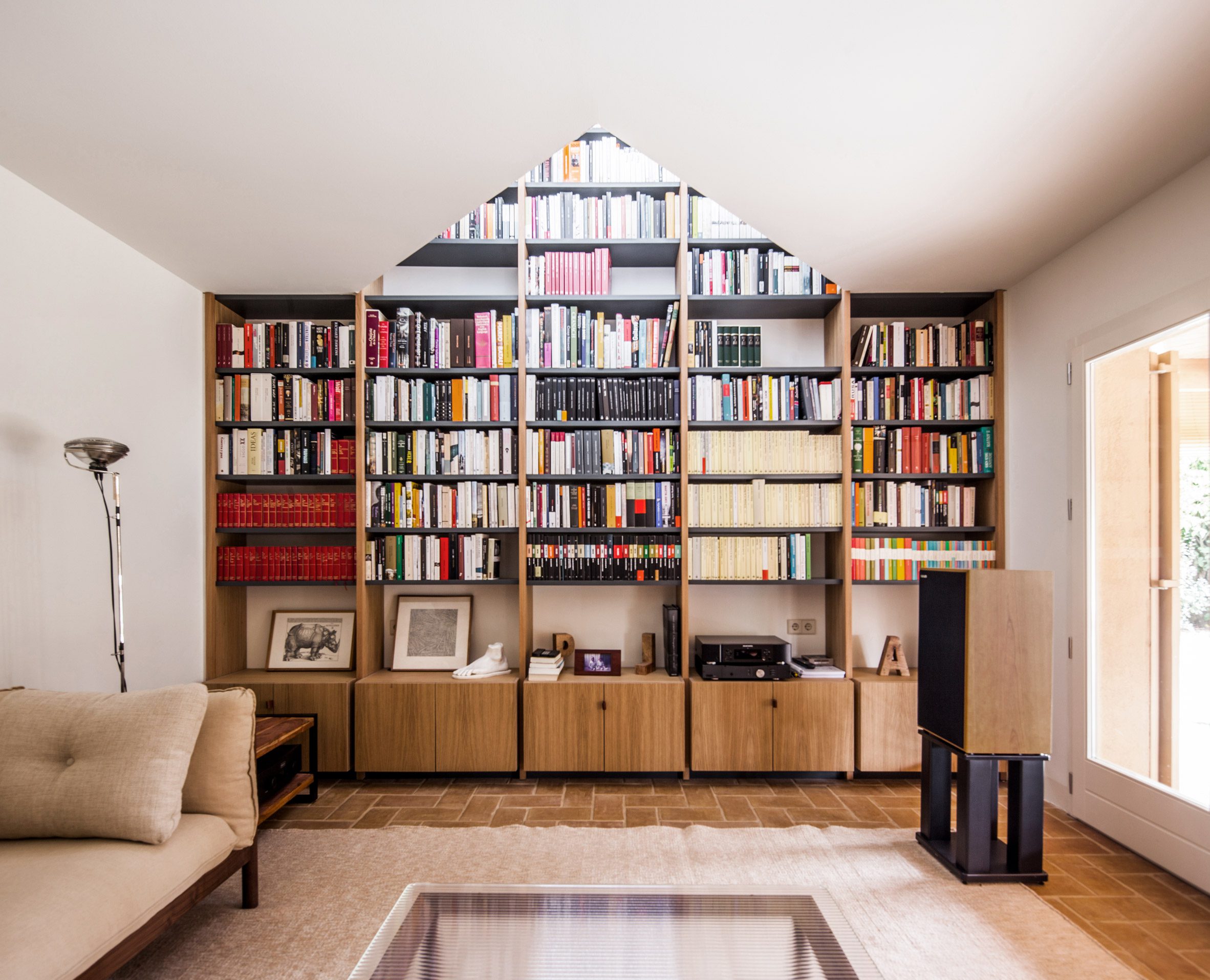 Built-in library shelves framed by a triangular opening in the ceiling